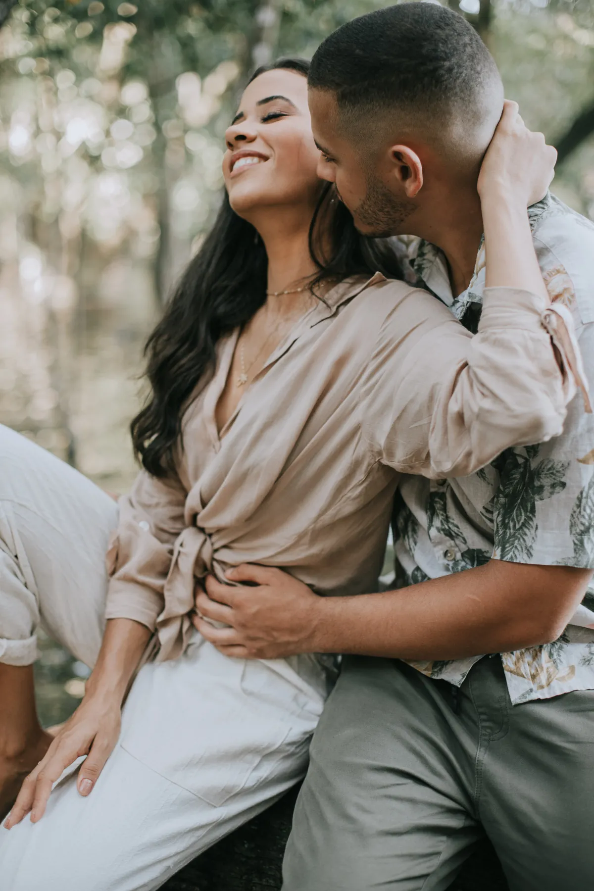 Casal abraçado e sorrindo num ensaio ao ar livre