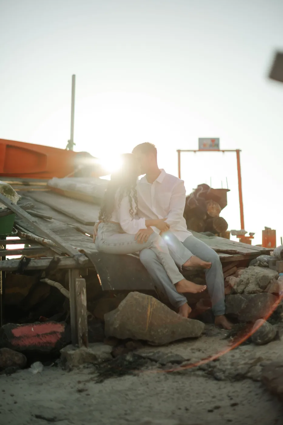 Casal sentado nos barcos, com o sol batendo entre os dois