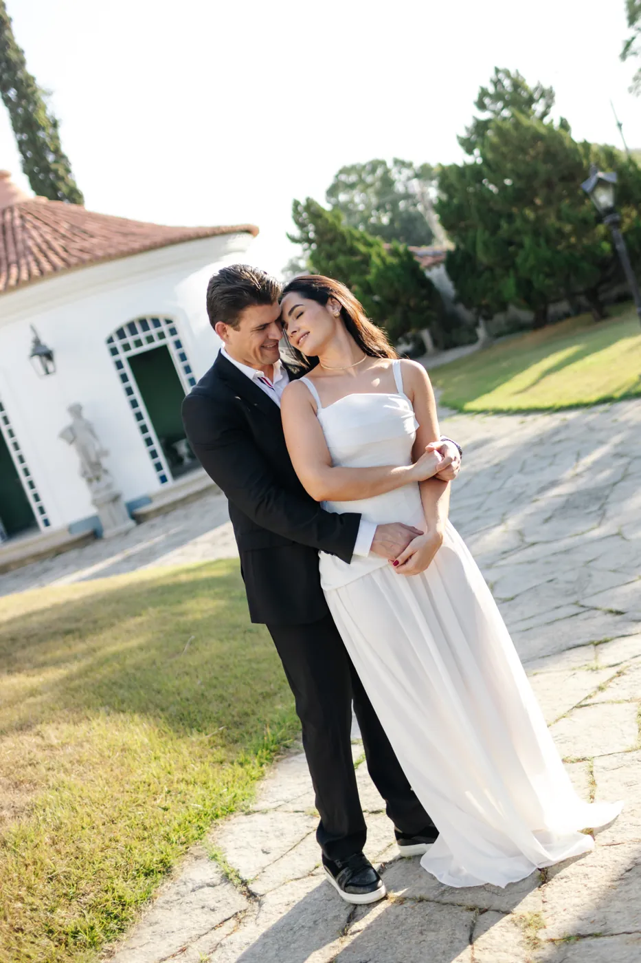 Casal abraçado no caminho de pedra do jardim, no fim da tarde