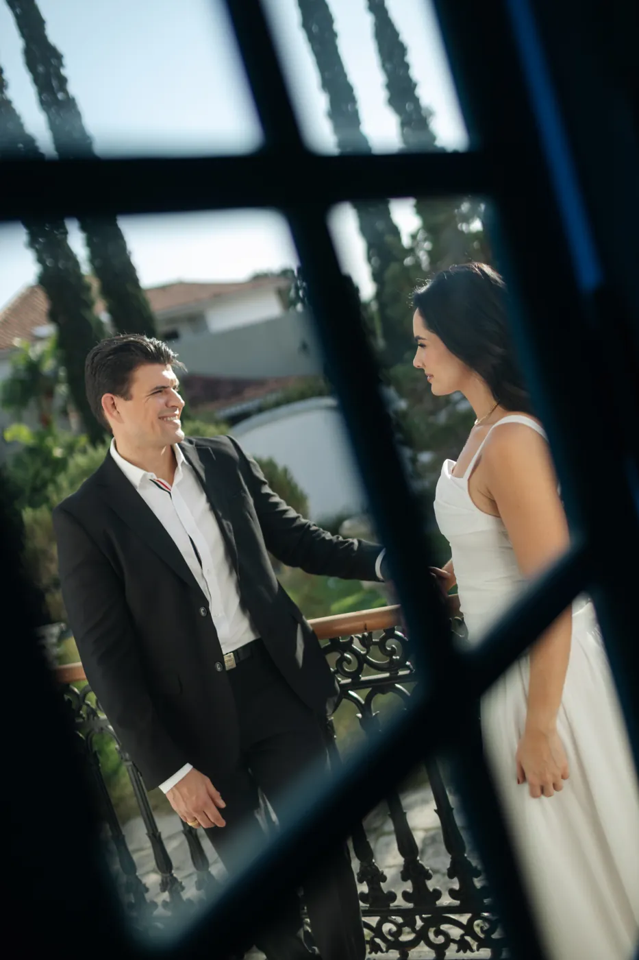 Casal na varanda visto pelo vitral da janela