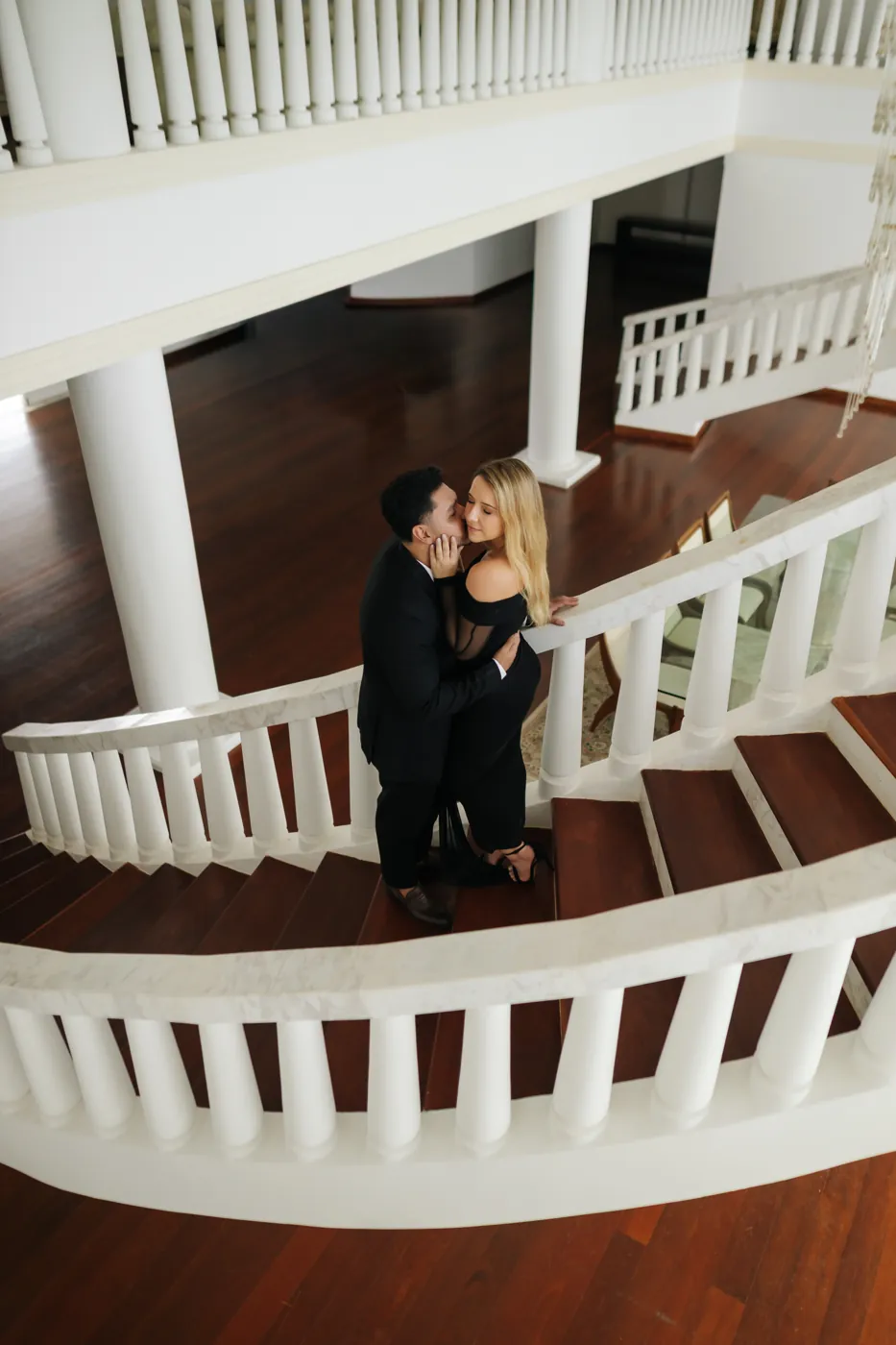Casal se beijando na escada em curva, visto de cima