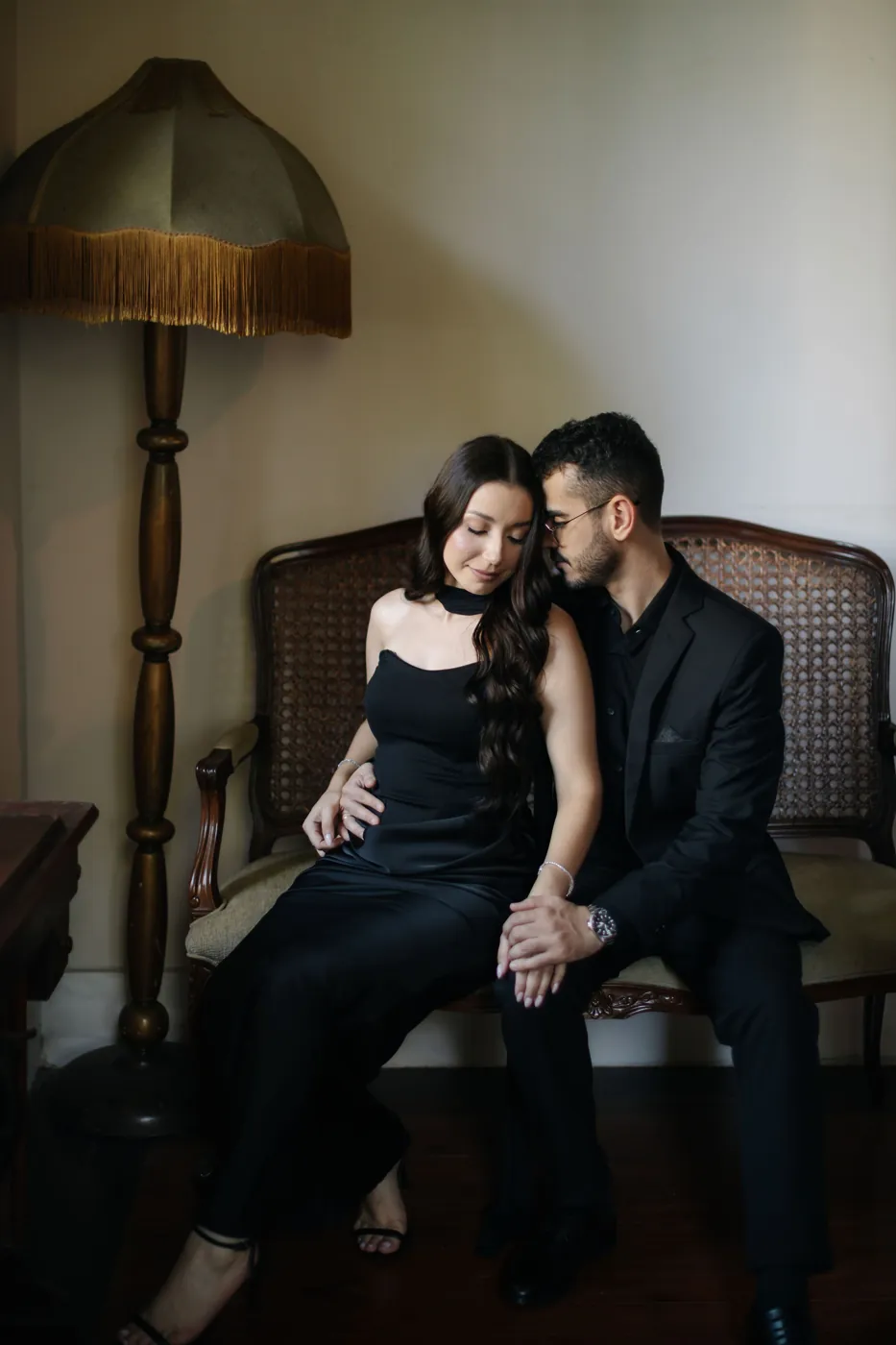 Casal sentado no sofá de palhinha, ao lado do abajur antigo