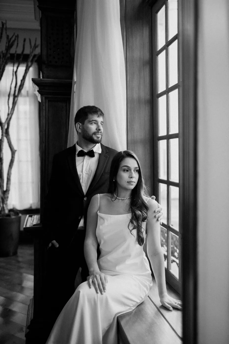 Casal na janela de madeira do hotel, em preto e branco