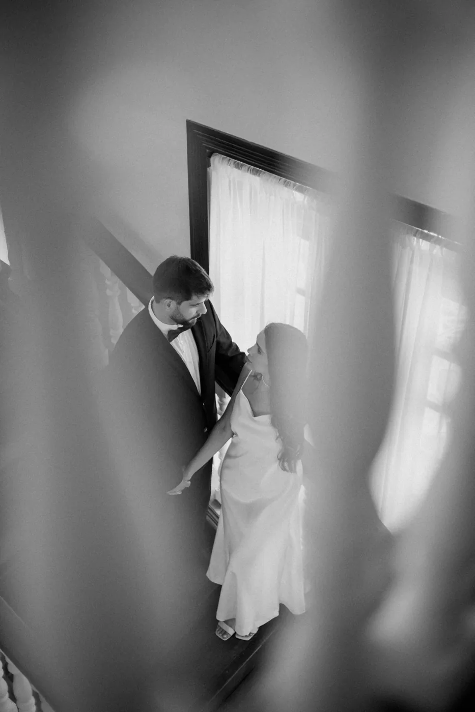 Casal visto de cima na escada, em preto e branco
