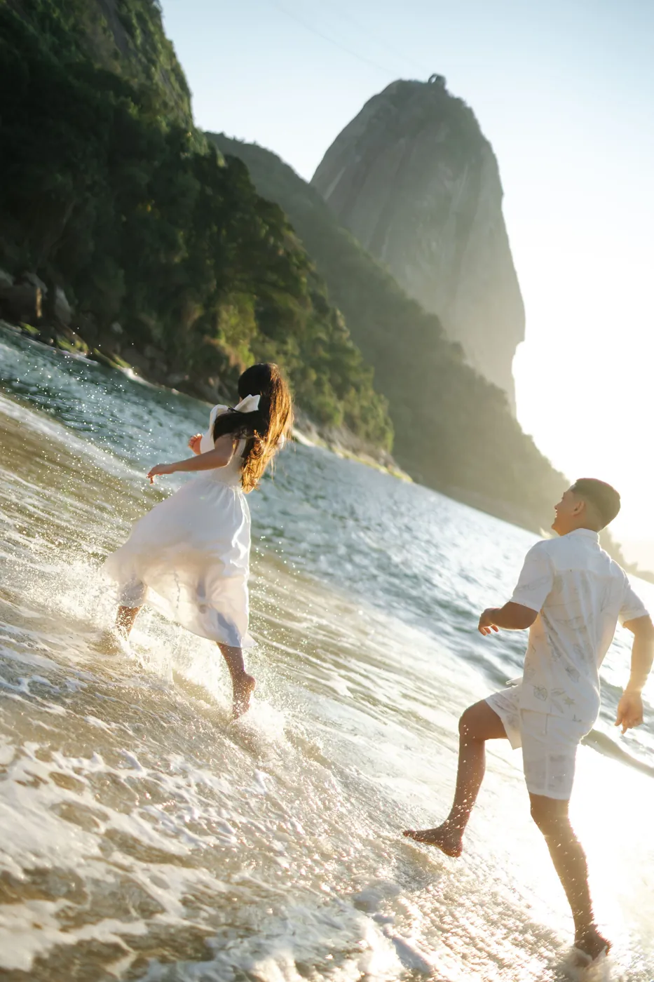 Casal correndo na beira do mar diante do Pão de Açúcar