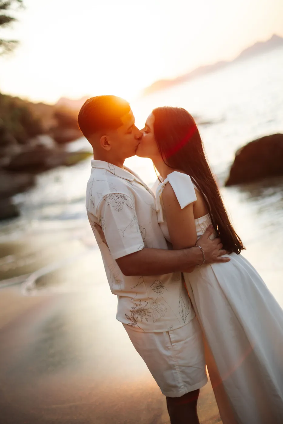 Casal se beijando no contraluz do pôr do sol