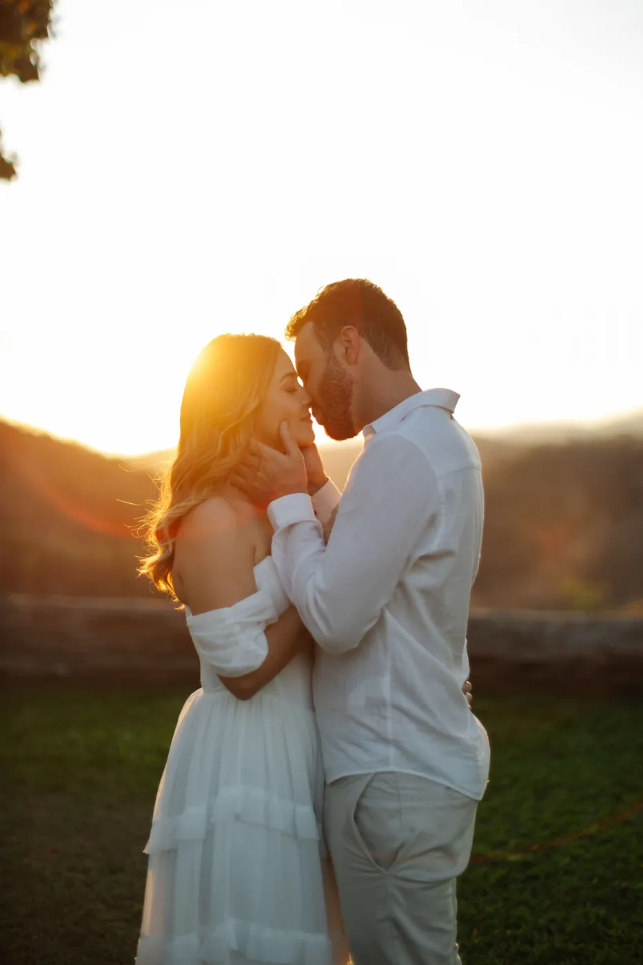 Casal testa com testa no contraluz do pôr do sol