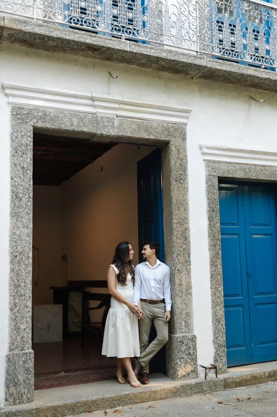Casal encostado na porta azul do casarão antigo